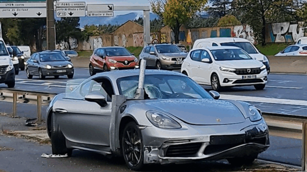 Voiture de sport accidentée encastrée dans une barrière de sécurité sur une autoroute, avec d'autres véhicules circulant en arrière-plan